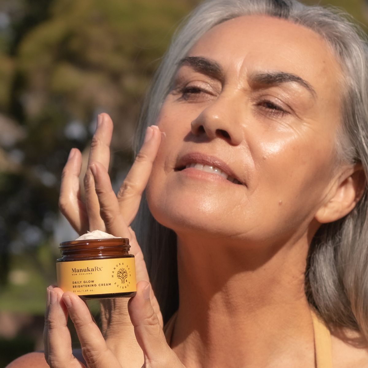 Woman applying ManukaRx Vitamin C Daily Glow Brightening Moisturiser to her face